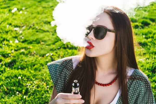 Feliz moda sonriente Mujer en gafas de sol fumar vapor en la calle, humo — Foto de Stock