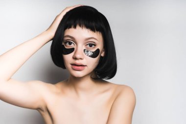 güzel beyaz saçlı kız siyah saçlı, Siyah Silikon yamalar gözlerinin altındaki elini kafasına koydu.