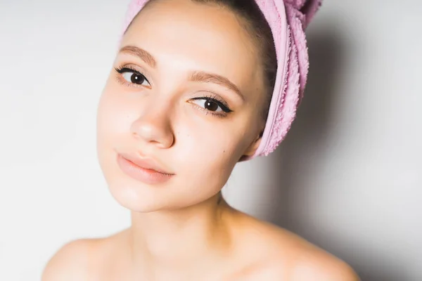 Όμορφη κοπέλα με καθαρό δέρμα και ένα ροζ πετσέτα στο κεφάλι της, εξετάζοντας τη φωτογραφική μηχανή — Φωτογραφία Αρχείου