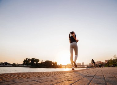 Spor fitness kız nehirde, güneşin batımında çalışıyor