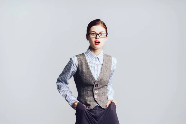 Hermosa joven en gafas con lápiz labial rojo en poses chaleco gris — Foto de Stock