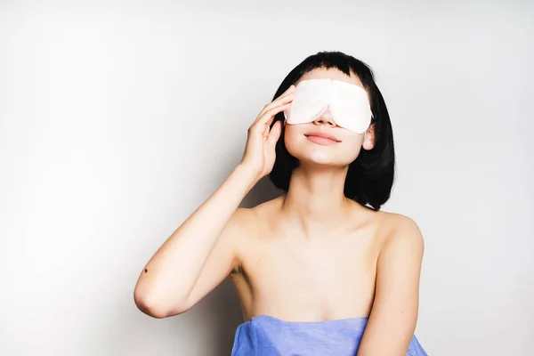 Jovem menina atraente com sorrisos de cabelo preto, em seus olhos máscara branca — Fotografia de Stock