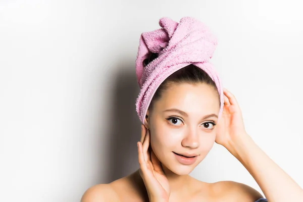 Jovem bonito menina com pele limpa, com uma toalha rosa na cabeça sorrindo, olhando para a câmera — Fotografia de Stock