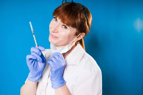 Doctora adulta en bata médica blanca, sosteniendo la jeringa, sonriendo — Foto de Stock