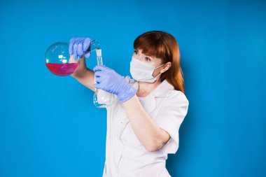 kız beyaz bir elbise içinde bir deneyim reaktifler onun hands.the kadın maskeli bir şişeye yapar tutar