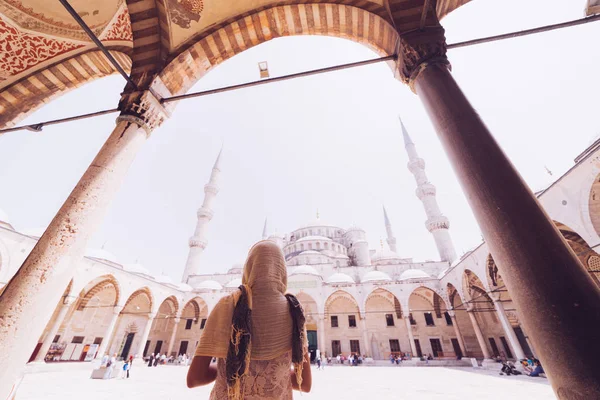 Молода жінка, яка подорожує в хедкарфі, стоїть на синьому тлі мечеті. Подорожі під час літніх канікул — стокове фото