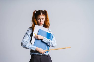 Kız iki kuyruklu ve bir mavi klasör, cetvel ve elleri kalem öfkeyle kameraya görünüyor
