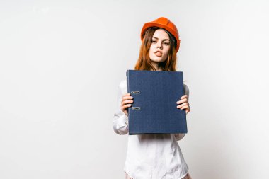 turuncu bir koruyucu kask içinde kendine güvenen genç kız mavi klasör belgeler için tutar