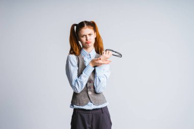 bir gri yelek üzgün üzgün kız gözlük elinde tutar.