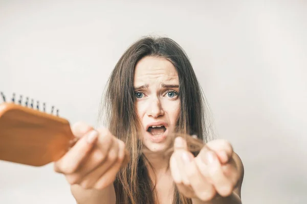 Jovem triste mostra seu cabelo caiu, segura um pente de madeira — Fotografia de Stock