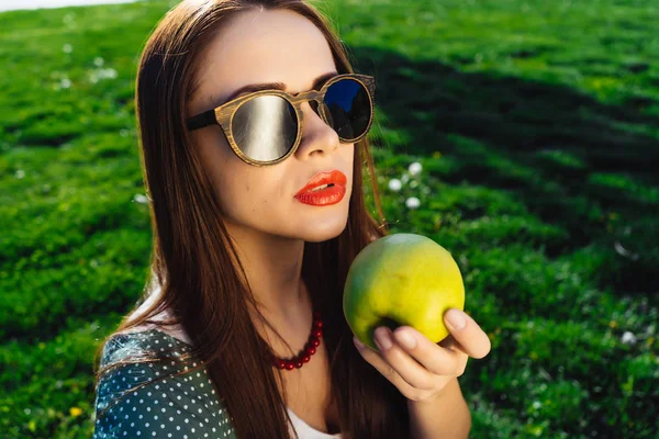 Mujer de moda en gafas oscuras come gafas de sol apple.Wooden — Foto de Stock