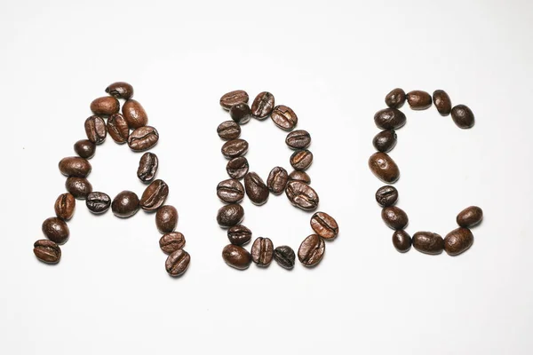 Σε φόντο λευκό ψέμα κόκκοι μυρωδάτο καφέ με τη μορφή των γραμμάτων abc — Φωτογραφία Αρχείου