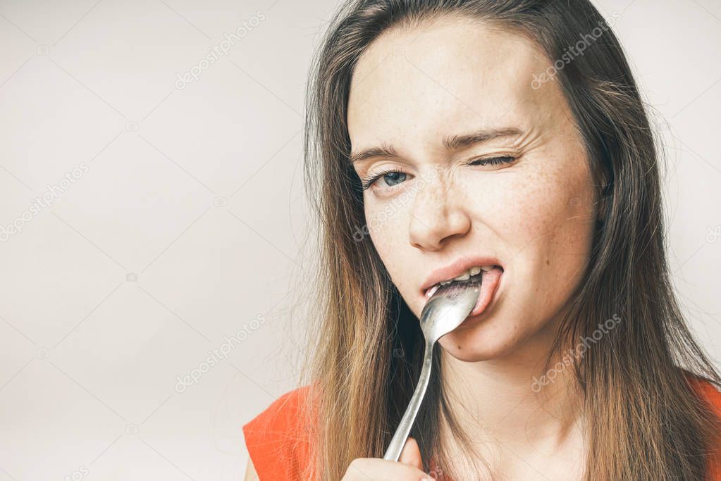 Hangry woman eating spoon. the girl winks at the camera, isolated