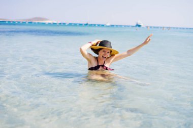 şapkalı ve güzel bir mayo içinde bir kız denizde banyoları. mutlu yaz tatili denizde
