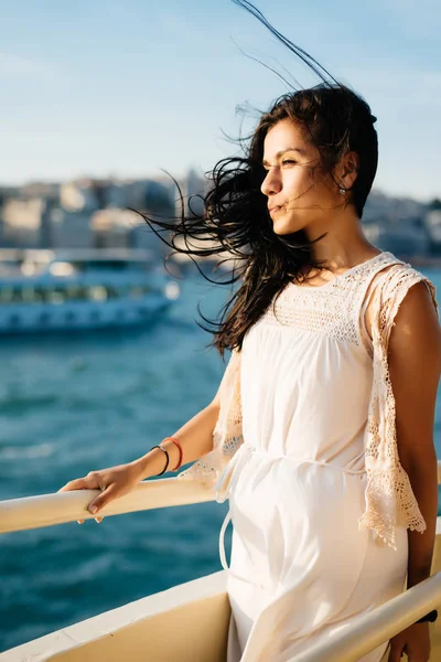 Bright sexy girl traveler floats by boat against the background of the city at sunset