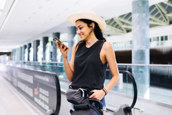 Woman with smartphone at airport. Young traveler checking boarding time with mobile phone app in terminalstation. — Stock Photo, Image