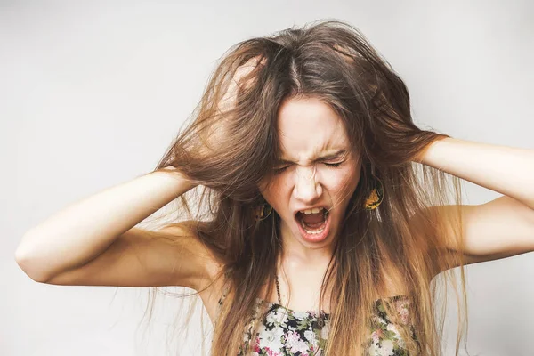 Μια νεαρή κοπέλα θυμωμένος κρατά το κεφάλι, κραυγές, τα μαλλιά της είναι αναμαλλιασμένος — Φωτογραφία Αρχείου