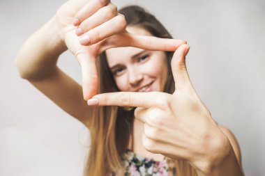 Gülümseyerek, kameraya bakarak kadının çerçeve el ile yapması