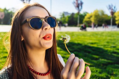 Komik gülümseyen mutlu kadın karahindiba üfleme güneş gözlüğü
