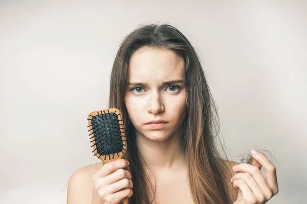 Θλιβερή νεαρή κοπέλα με τα ξανθά μαλλιά μια ξύλινη χτένα κρατά στα χέρια της — Φωτογραφία Αρχείου