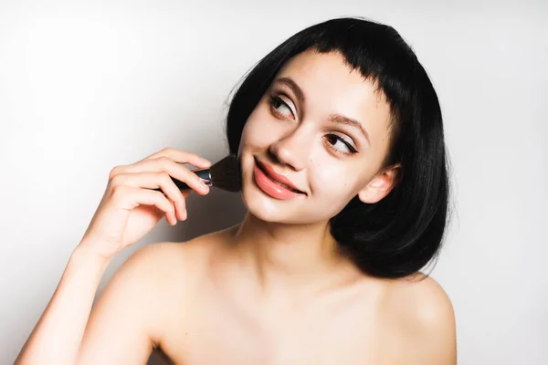 Ελκυστική νεαρή κοπέλα με τα μαύρα μαλλιά εφαρμογή μακιγιάζ με βούρτσα, smilin — Φωτογραφία Αρχείου