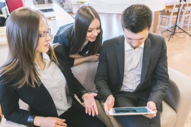 Genç başarılı adam ve siyah takım elbiseli 2 kız birlikte ofis, bak tablet vasıl iş