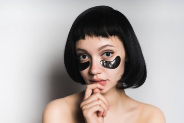 güzel siyah saçlı kız poz, kameraya bakarak gözlerinin altında Siyah Silikon yamalar ile
