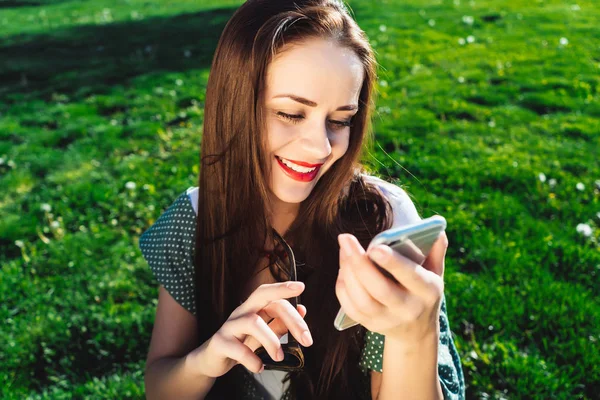 Mujer de mensajes de texto, sorprendido, hierba fondo de verano, sonriendo, mirando a su teléfono inteligente — Foto de Stock