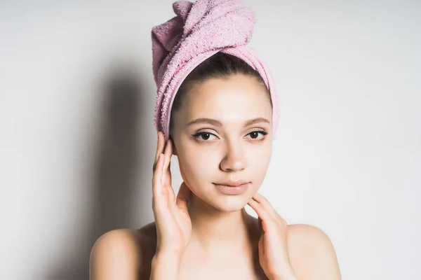 Hermosa chica con la piel limpia, con una toalla rosa en la cabeza mirando a la cámara — Foto de Stock