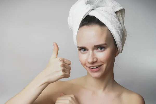 Женщина показывает большие пальцы вверх, с белым полотенцем на голове, улыбаясь — стоковое фото