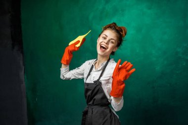 mutlu genç kız sarı bez holding, gülen portakal lastik eldiven giymiş siyah önlük