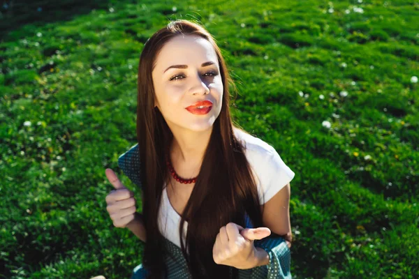 Mujer sonriente muestra pulgares hacia arriba, fondo de hierba, felicidad de verano — Foto de Stock