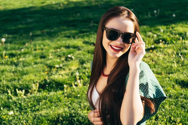 Красивая женщина на фоне травы, солнцезащитные очки, улыбка — стоковое фото