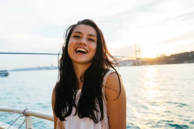 Genç kız gezgin bir yatta seyir ederken rahatlatır, gün batımı ve okyanus bakarak, arka plan üzerinde köprü. İstanbul 'un boğaz köprü