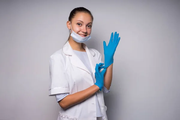 웃는 의사 소녀 흰색 의료 드레싱 가운 블루 장갑에 박 았 카메라에 보이는 — 스톡 사진