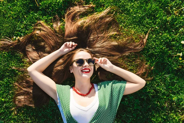 Super happy smiling woman in glasses on grass,top view above