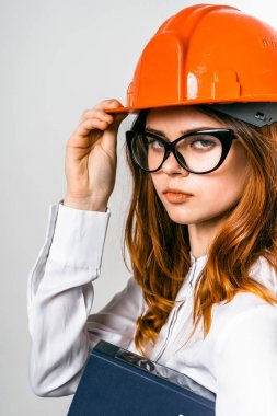gözlük ve turuncu bir koruyucu kask ile genç ciddi Kızıl saçlı kız kameraya doğru görünüyor
