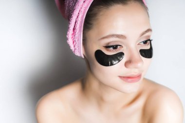 güzel genç kadın ile onun baş ve uzağa arıyorsunuz gözlerinin altındaki Siyah Silikon yamalar üzerinde pembe bir havlu ile temiz cilt
