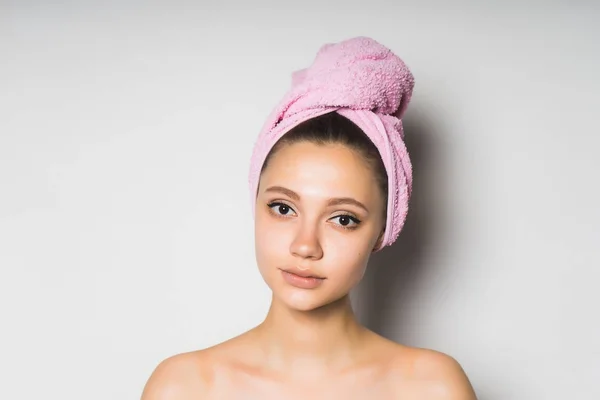 Bela menina com pele limpa, com uma toalha rosa na cabeça olhando para a câmera — Fotografia de Stock