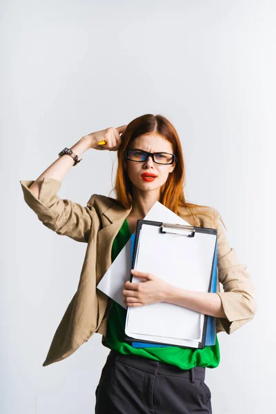Ein stylisches rothaariges Mädchen mit Brille, grünem Pullover, das an etwas denkt, hält die Dokumente in ihren Händen — Stockfoto