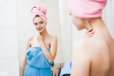 güzel genç kız kendini aynaya bakıyorum ve gülümseyen başında pembe havlu ile