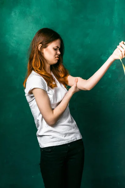 Menina triste em uma camiseta branca descontente com seus músculos em seu braço — Fotografia de Stock