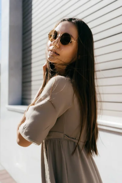 Menina atraente em um vestido bege, em óculos de sol posando ao sol — Fotografia de Stock