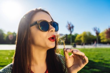 Mutlu gülümseyen komik surat kız darbe karahindiba, yaz güneş gözlüğü, günbatımı