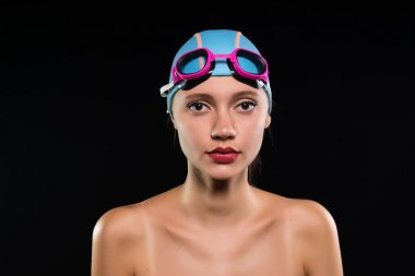 Kendine güvenen genç atletik kız yüzücü bir yüzme kap ve gözlük kameraya benziyor