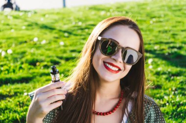 Mutlu moda gülümseyen kadın güneş gözlüğü vape Street, duman Sigara