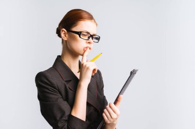 Kendine güvenen kız siyah bir takım elbise ve gözlük bakar, bir defter, önemli bir şey hakkında düşünüyor