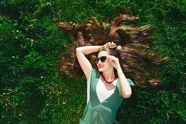 Happy fashion style smiling woman relaxing,joy,funny,lies on the green grass