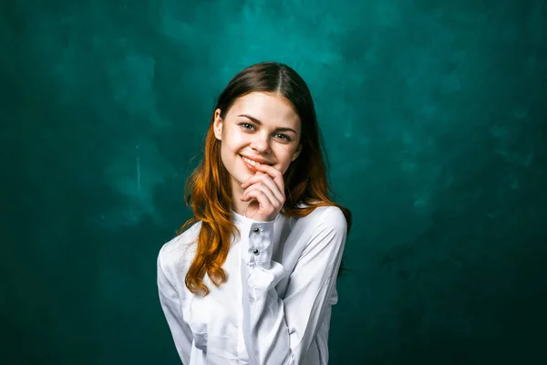 Sorridente giovane ragazza carina in camicia bianca, tenendo una mano vicino al viso, in posa — Foto Stock