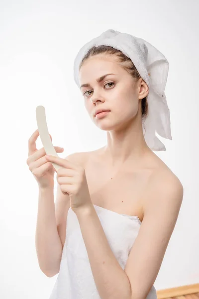 Young beautiful girl with clean skin, with a white towel on her head sawing her nails with a filing — Stock Photo, Image